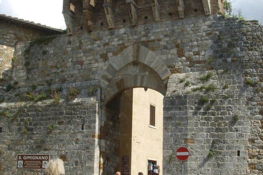 A stone archway leading into a building with a sign reading 'S. Gimignano.' 3