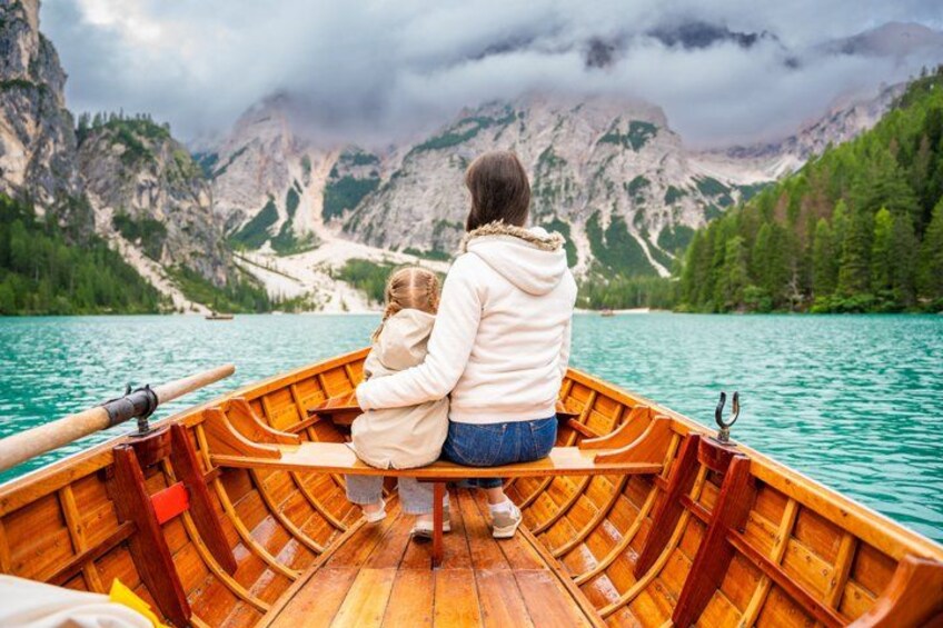 A wooden boat on a calm lake with mountains in the background. 3