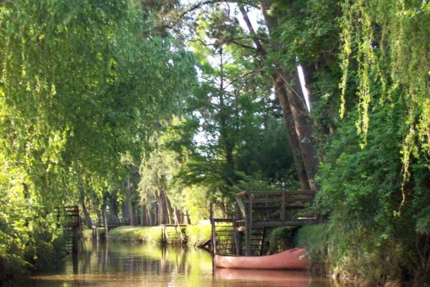 A calm river with a wooden bridge and a red canoe. 5