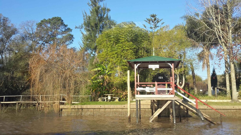 A wooden observation deck over water with a green roof, surrounded by trees and a picnic table. 4
