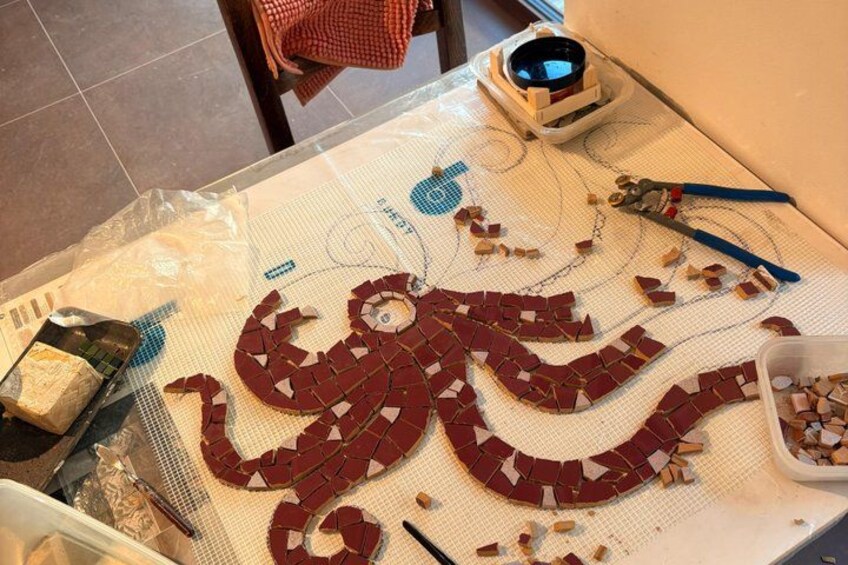 A table with a mosaic of red tiles, tools, and a plastic bag. 5