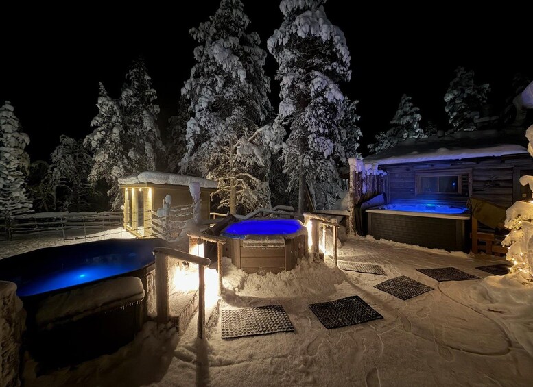 A snow-covered outdoor area with heated hot tubs and a wooden cabin. 5