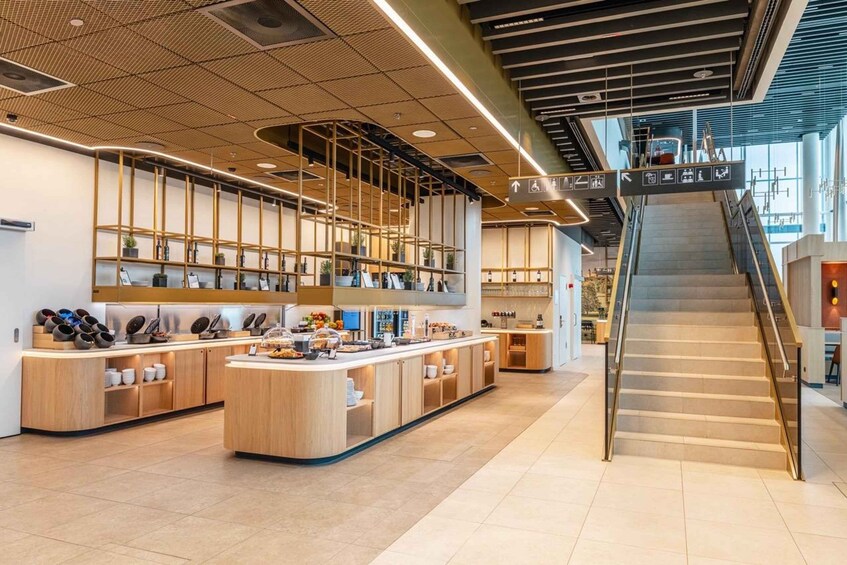 A modern cafe interior with a central counter, wooden shelves, and a staircase. 1