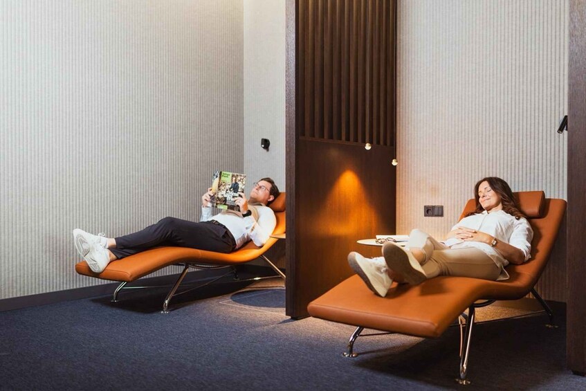 Two people lying on reclining chairs in a room with vertical paneling. 3