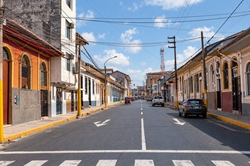 A street lined with buildings, a clear sky, and a distant tower. 5
