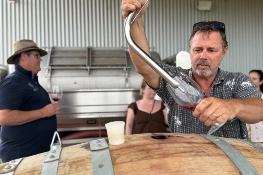 A person pouring wine from a glass into a barrel. 5