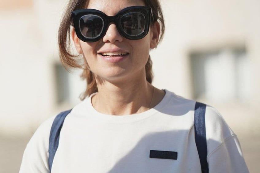 A person wearing a white shirt with a black patch and blue straps. 3