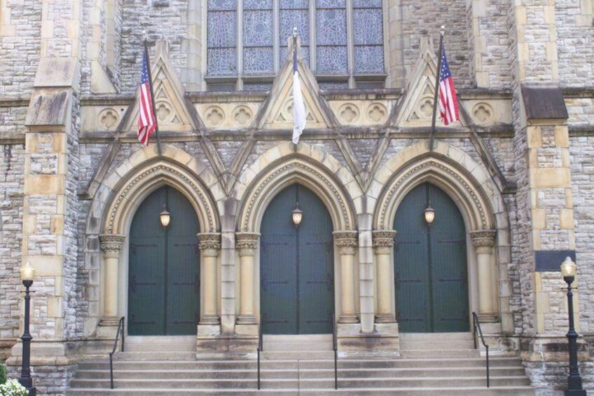 A stone building with three arched doors, each with an American flag. 4