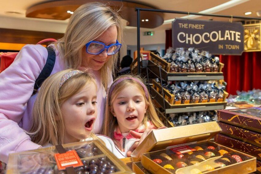A woman and two children looking at chocolates in a store. 2