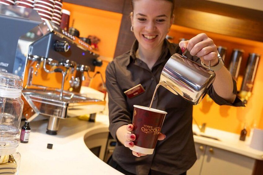 A person pouring a drink from a metal pitcher into a disposable cup. 4