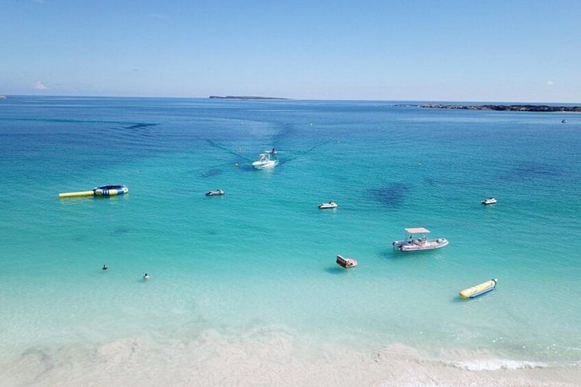 A clear turquoise sea with several small boats and a yellow raft. 4