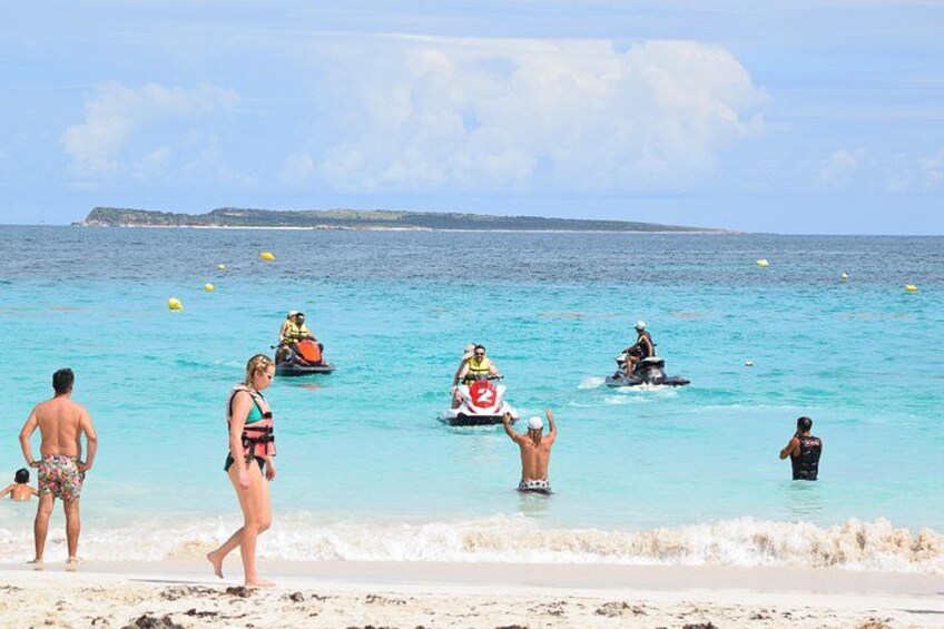 A beach with people walking and riding jet skis. 2