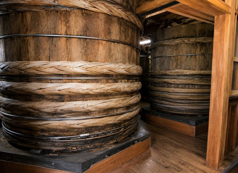 Large wooden barrels with metal bands, stacked in a wooden structure. 3
