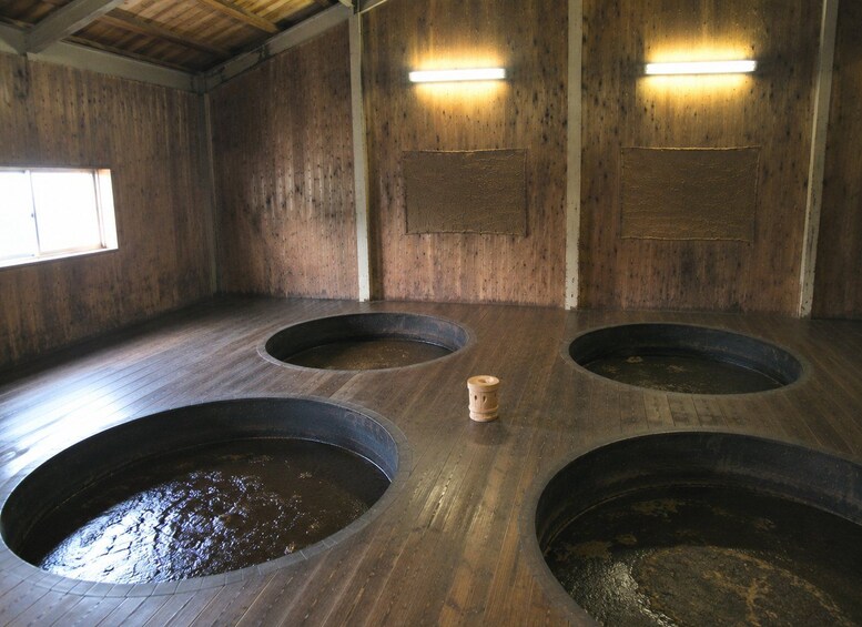 A wooden interior with four circular basins and a wooden stool. 4