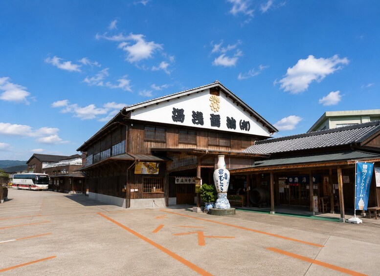 A traditional Japanese building with a sign in Japanese, a parking lot, and a bus in the background. 2