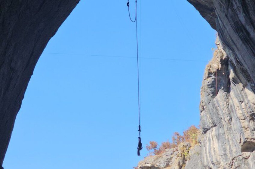 A person bungee jumping from a rock arch. 4