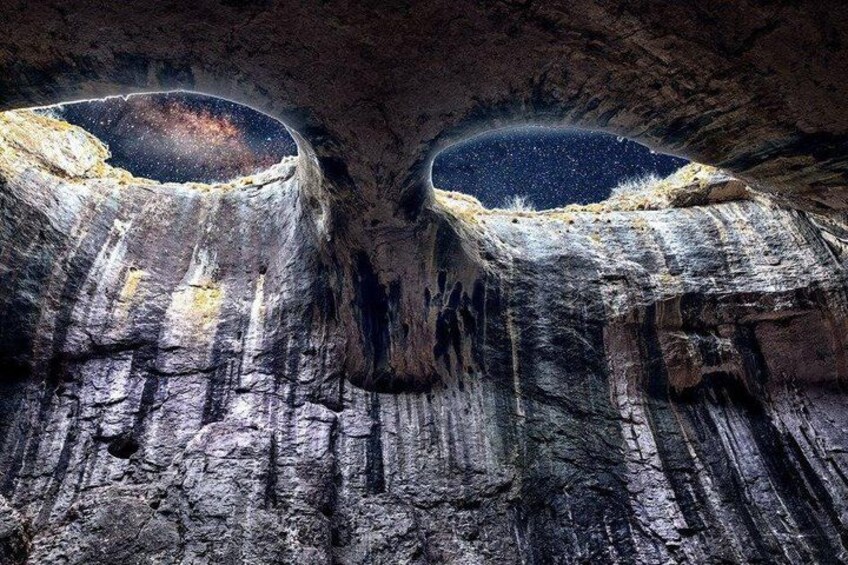 A cave with two large openings revealing a starry sky. 2