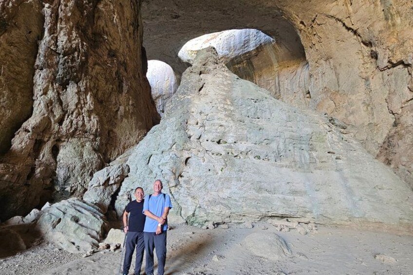 Two people standing in a rocky cave with large boulders. 5