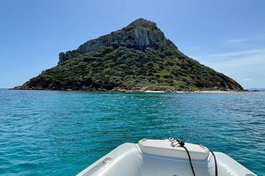 A boat on turquoise water with a rocky island in the background. 3