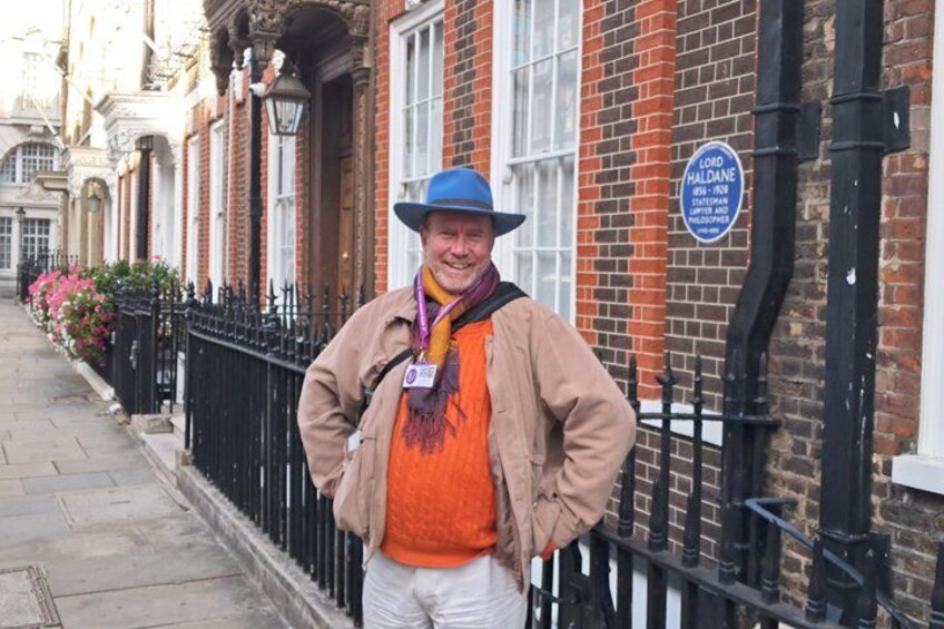 A person standing on a sidewalk next to a brick building with a sign that reads 'Lord Haldane.' 2
