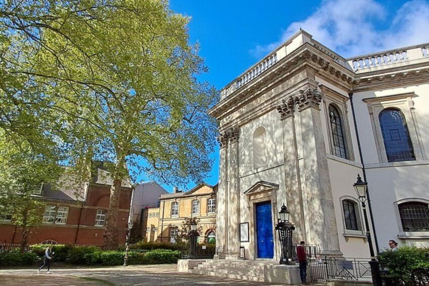 A classical building with a blue door, surrounded by trees and other buildings. 4