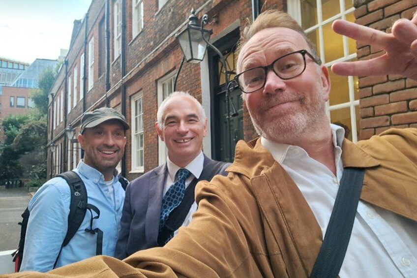 Three people taking a selfie in front of a brick building with windows and a door. 3
