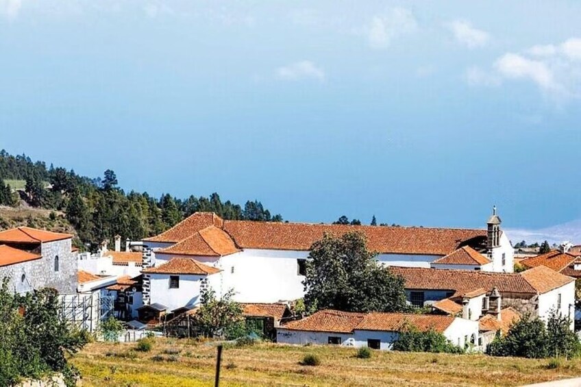 A coastal village with white buildings and red-tiled roofs, surrounded by greenery and hills. 4