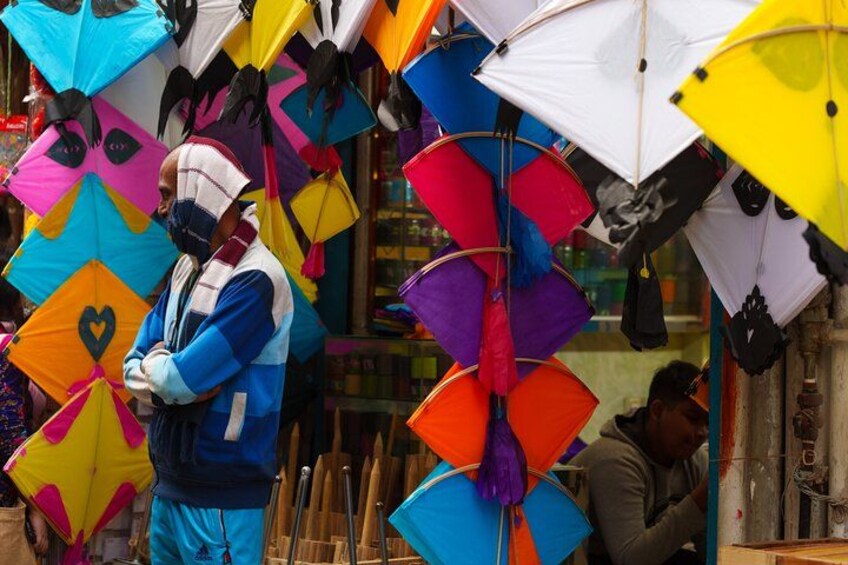 A person standing in front of a variety of colorful kites. 3