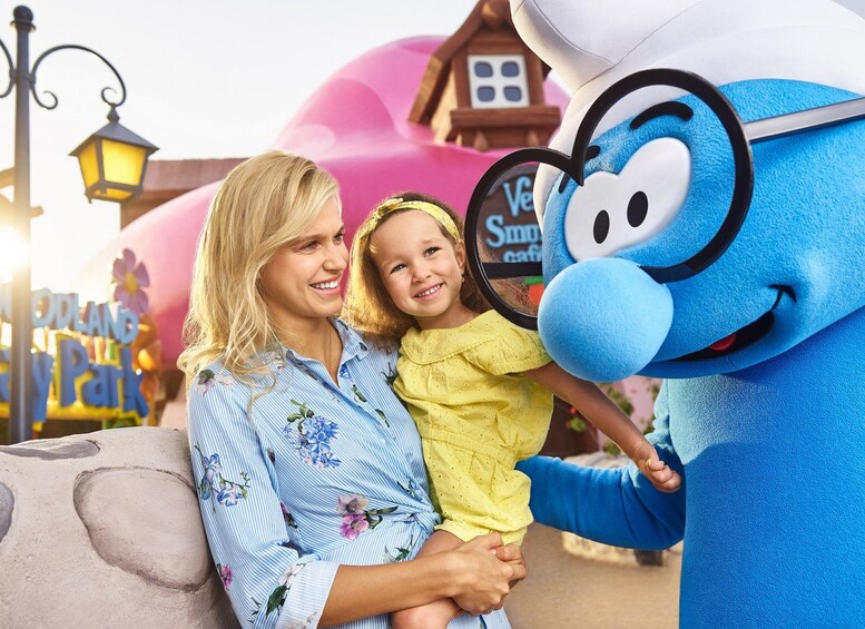 A person in a blue costume with a hat and glasses, holding a child. 3