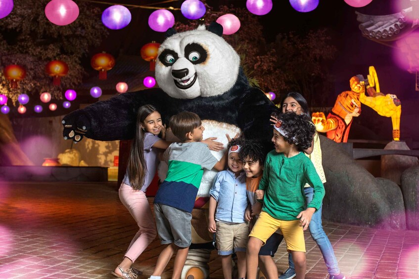 A panda mascot interacting with children at a nighttime event. 4