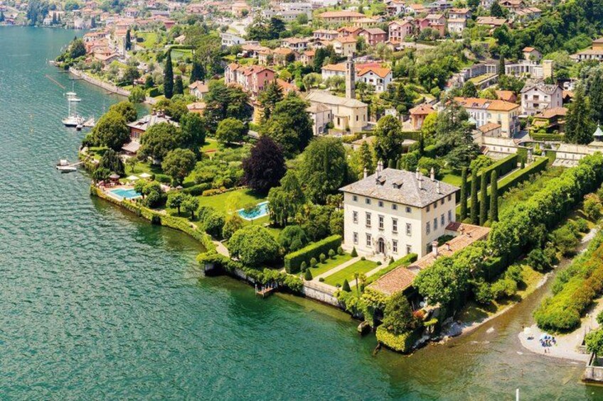 A lakeside town with a prominent white building surrounded by lush greenery and a clear blue lake. 5