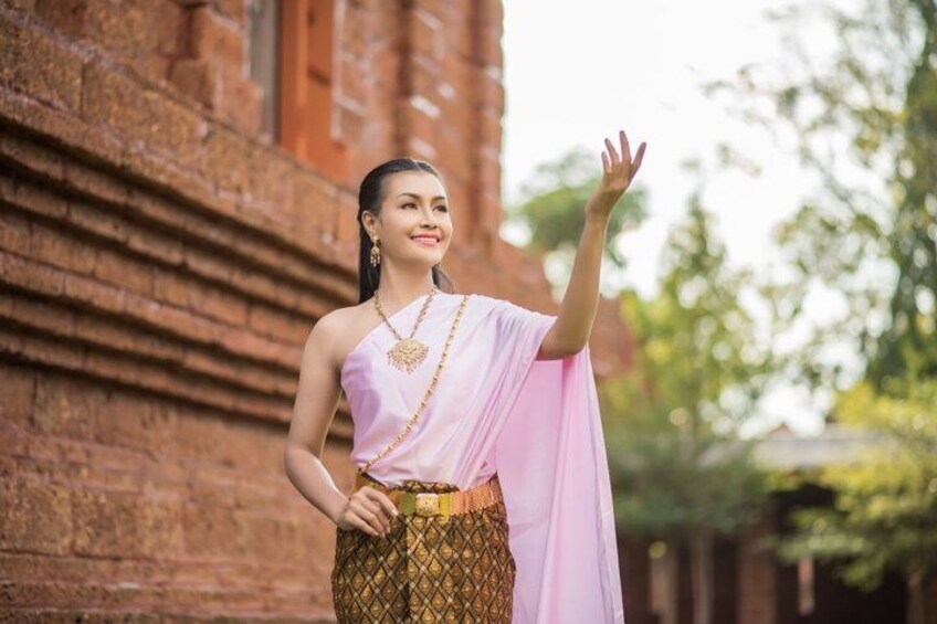 A person in traditional attire standing in front of a brick building. 4