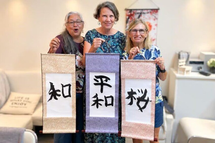 Three individuals holding framed signs with Japanese characters. 2