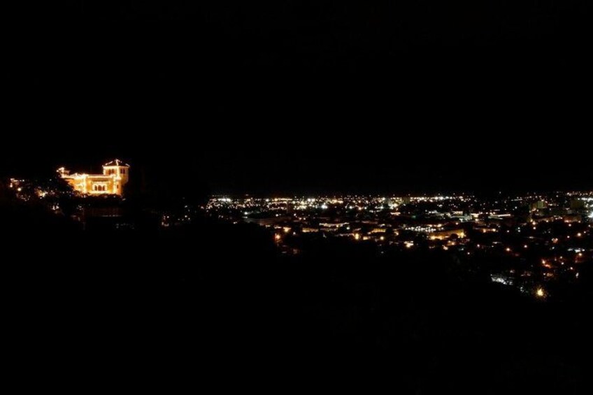 A cityscape at night with illuminated buildings and a prominent structure on the left. 3