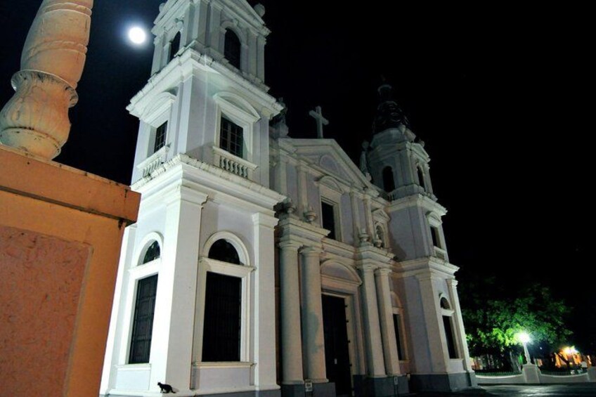 A church with a bell tower and a statue, illuminated at night. 5
