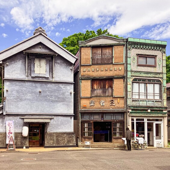 A row of three-story buildings with a mix of architectural styles, including a wooden structure and a brick building with a green facade. 3