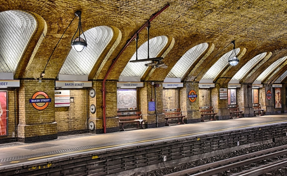 A Baker Street underground station with brick walls, arched ceilings, and multiple signs indicating directions. 2