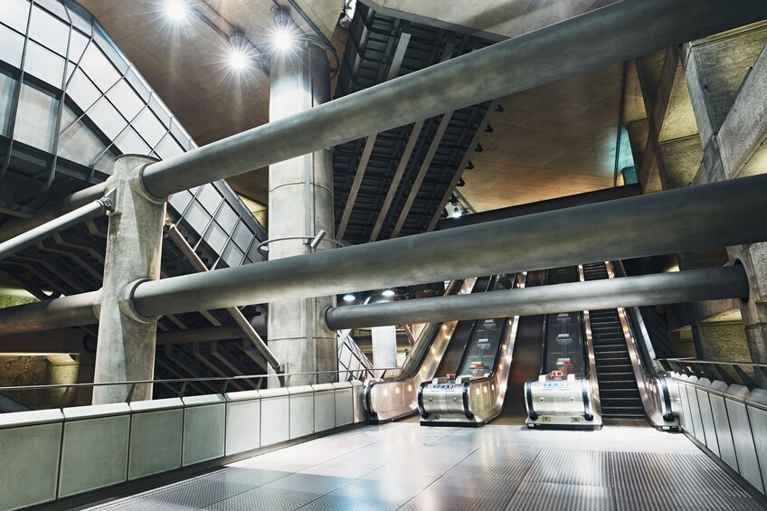 An indoor escalator area with metal railings and concrete pillars. 3