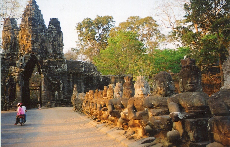 Lines of statues with temple in the background in Roluos, Cambodia 5