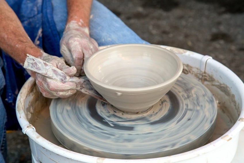 Closeup of hands carving bottom of bowl on pottery wheel 5