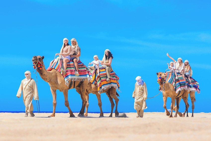 Un groupe de personnes chevauchant des chameaux sur une plage désertique. 5