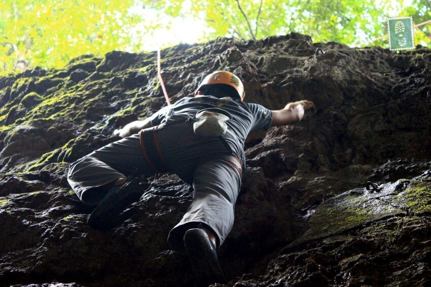 View from below of man rock climbing in Vang Vieng, Laos