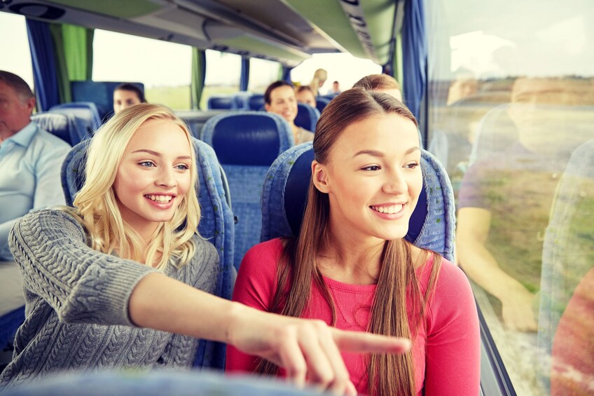 Two seat mates point to sights outside bus window