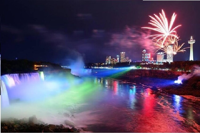 Niagara Falls lit up at night with firework show nearby