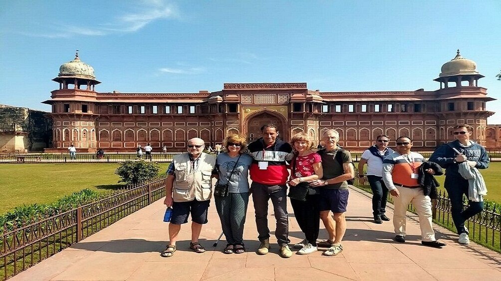 A group of people standing in front of a large, historic building with domed towers. 1