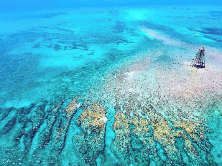 Une mer d’un bleu profond, avec un récif corallien et une petite île surmontée d’un phare. 5