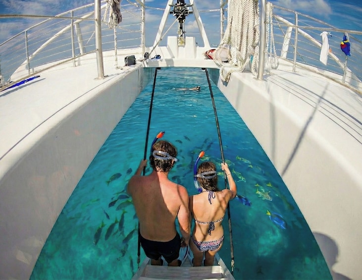 Deux personnes font de la plongée avec tuba dans une piscine aux eaux bleues et cristallines, à bord d’un bateau. 1