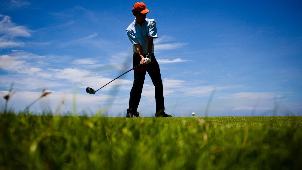 View from ground of golfer getting ready to swing club 3