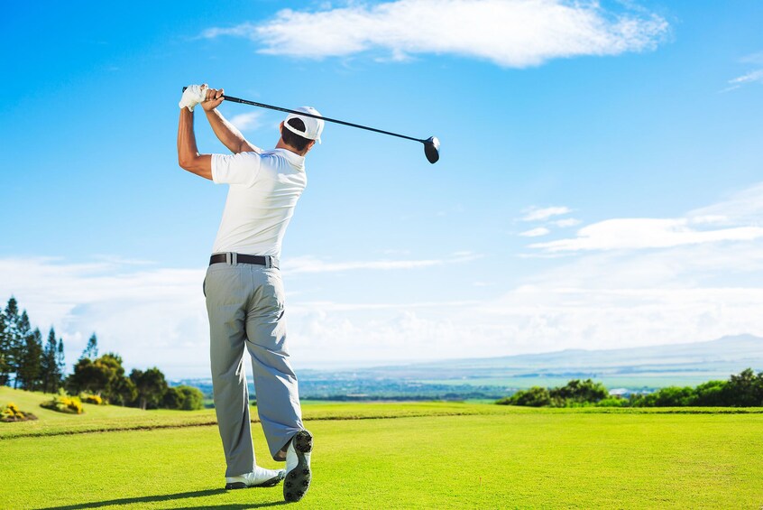 View from behind of golfer swinging club on a sunny day