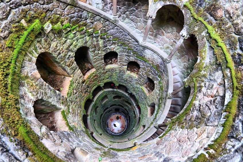 A spiral stone staircase with moss growth and multiple openings. 1